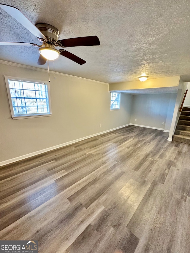 interior space with crown molding, a textured ceiling, wood finished floors, baseboards, and stairs