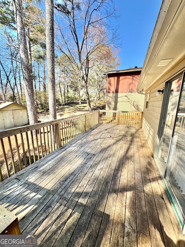 wooden terrace featuring an outdoor structure and a shed