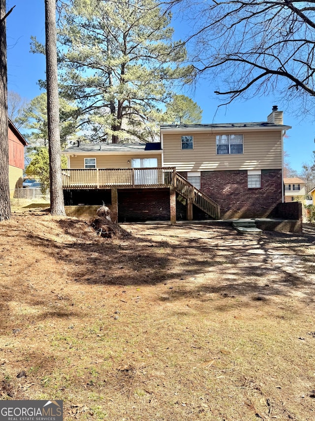 rear view of property featuring brick siding, a chimney, stairway, and a wooden deck