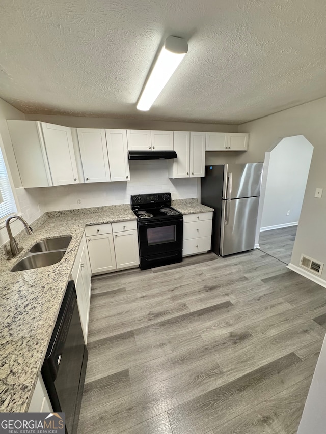 kitchen featuring under cabinet range hood, a sink, visible vents, white cabinetry, and black appliances