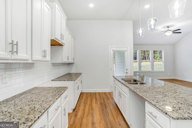 kitchen with pendant lighting, sink, light hardwood / wood-style floors, and white cabinets