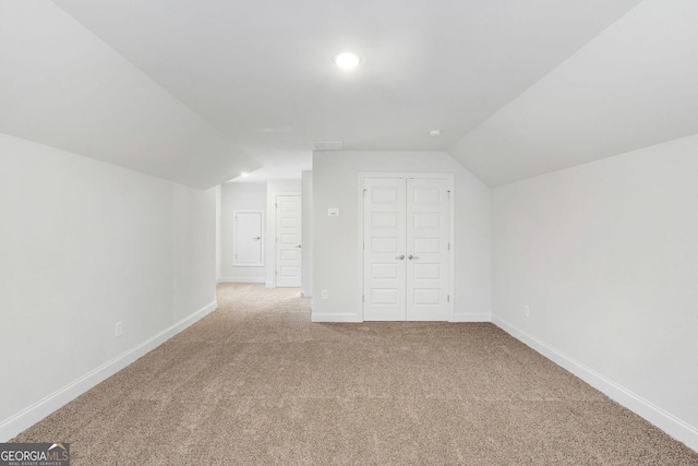 bonus room featuring vaulted ceiling and light carpet