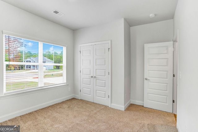 unfurnished bedroom featuring light carpet and a closet