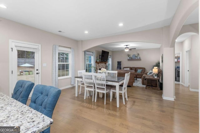 dining space with a fireplace, light hardwood / wood-style floors, and ceiling fan