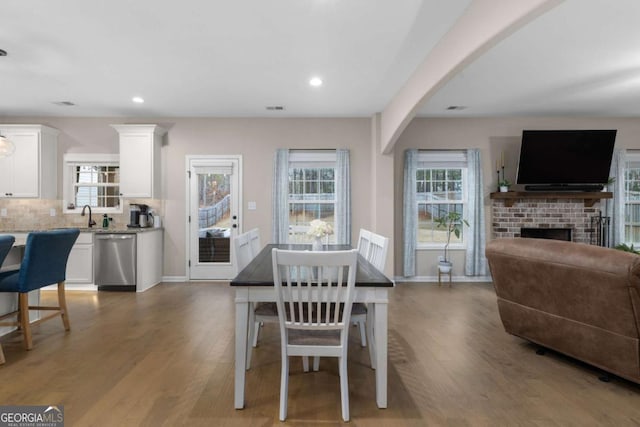 dining area with sink, hardwood / wood-style flooring, and a fireplace