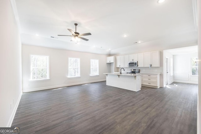 kitchen featuring visible vents, white cabinetry, open floor plan, appliances with stainless steel finishes, and a center island with sink