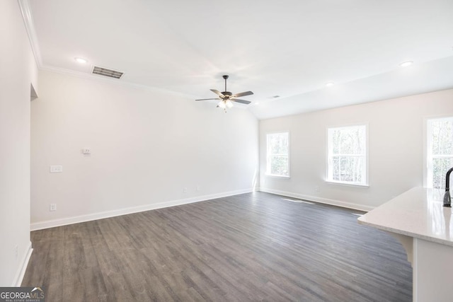 unfurnished living room with dark wood-style floors, a healthy amount of sunlight, and baseboards