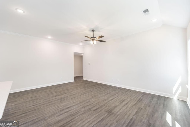 spare room featuring dark wood-type flooring, a ceiling fan, visible vents, baseboards, and ornamental molding