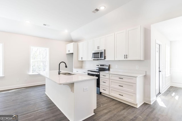 kitchen with appliances with stainless steel finishes, a kitchen island with sink, light countertops, white cabinetry, and a sink