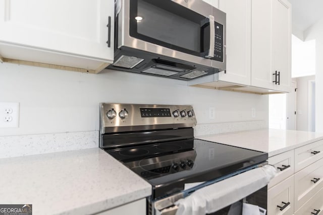 kitchen featuring white cabinetry, stainless steel appliances, and light stone counters