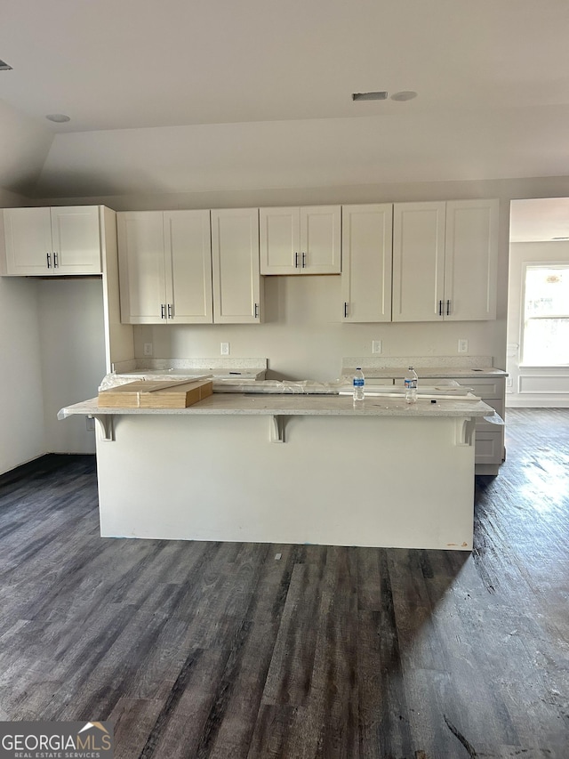 kitchen featuring white cabinetry, a center island with sink, and a kitchen bar