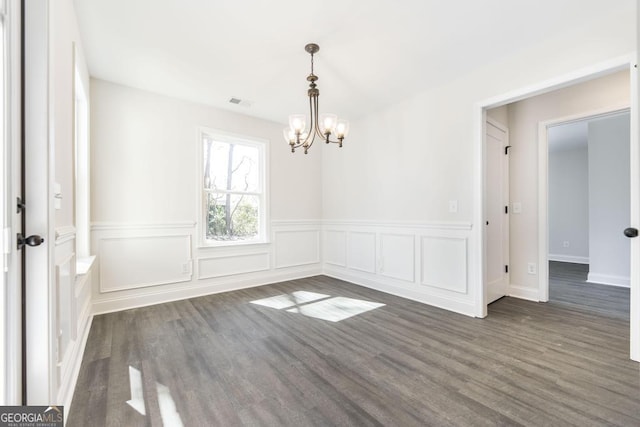 empty room with an inviting chandelier, visible vents, and wood finished floors