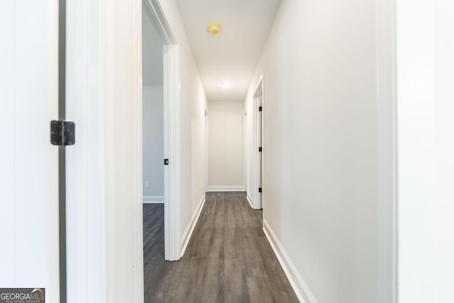 hallway featuring dark wood finished floors and baseboards