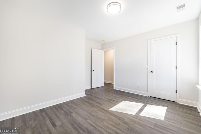 unfurnished bedroom featuring baseboards, visible vents, and wood finished floors