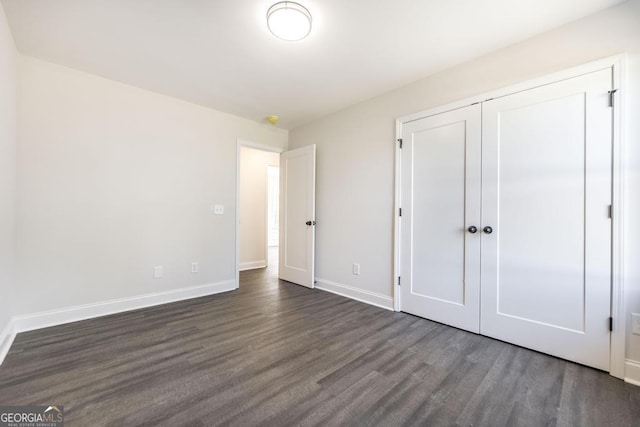 unfurnished bedroom featuring dark wood-style floors, a closet, and baseboards