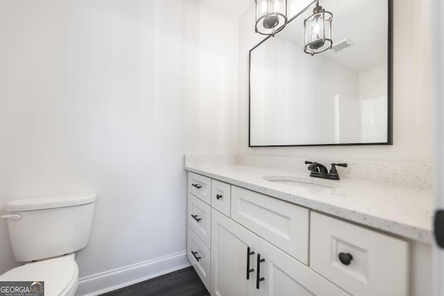 bathroom with toilet, wood finished floors, visible vents, vanity, and baseboards