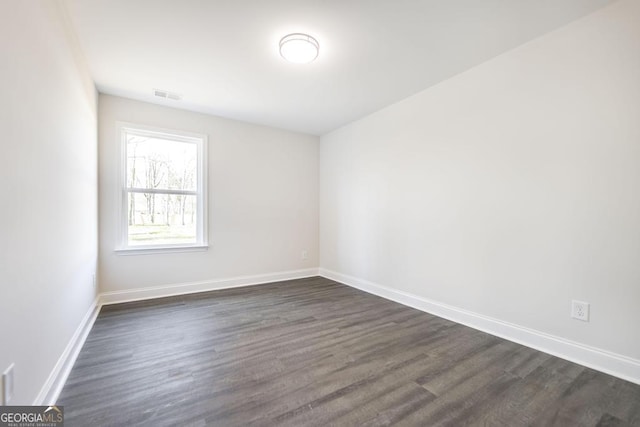 unfurnished room featuring dark wood-type flooring and baseboards