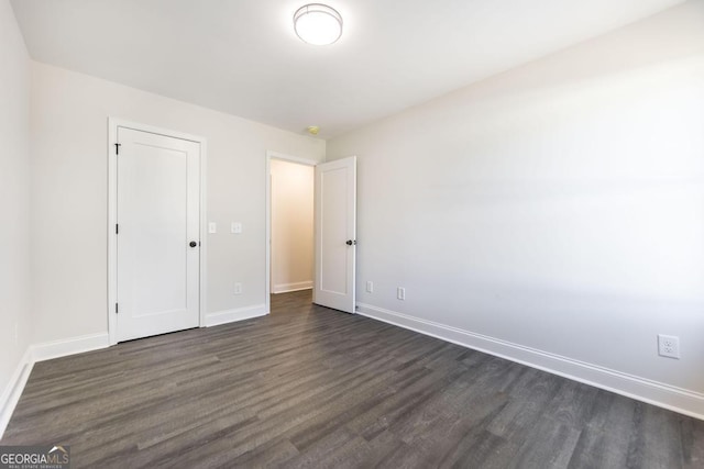 unfurnished bedroom featuring baseboards and dark wood-style flooring