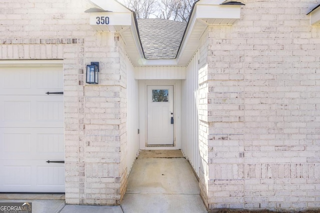 view of exterior entry with roof with shingles