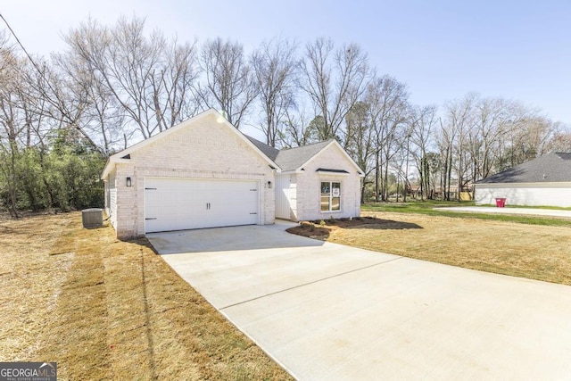 view of front of home featuring central AC unit, an attached garage, brick siding, concrete driveway, and a front yard