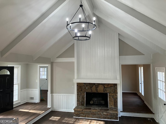 unfurnished living room featuring a stone fireplace, a chandelier, dark hardwood / wood-style floors, and beamed ceiling