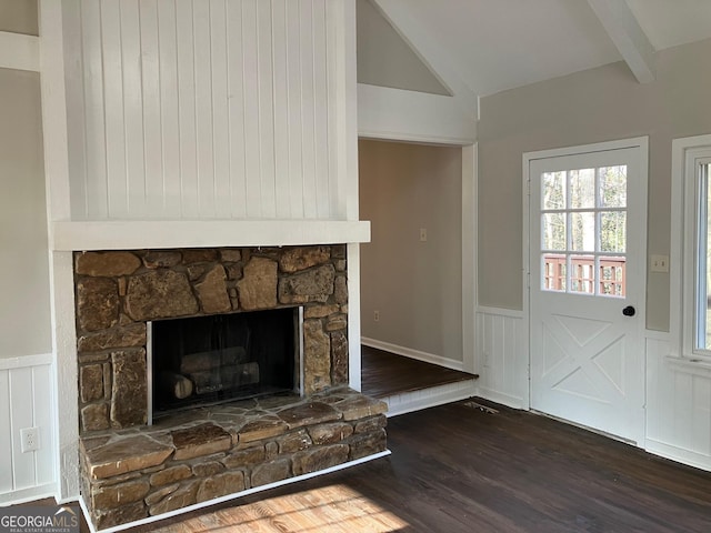 interior space with dark wood-type flooring, a stone fireplace, and vaulted ceiling with beams