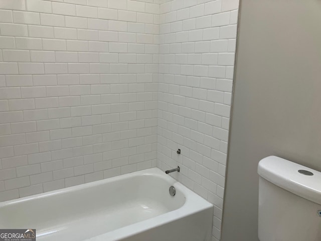 bathroom with tiled shower / bath combo and toilet