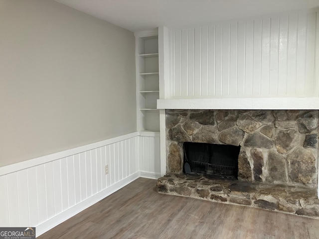 room details with wood-type flooring, a fireplace, and built in shelves