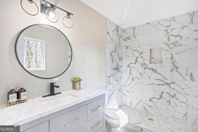 bathroom featuring vanity, toilet, and a tile shower