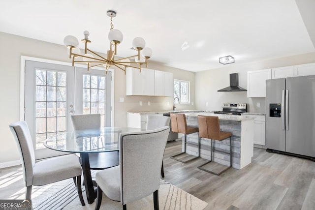 dining space with french doors, a notable chandelier, sink, and light wood-type flooring