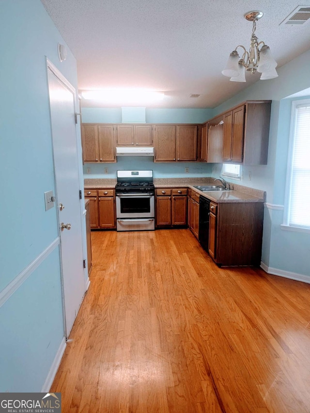 kitchen featuring black dishwasher, light wood-style flooring, light countertops, under cabinet range hood, and gas stove