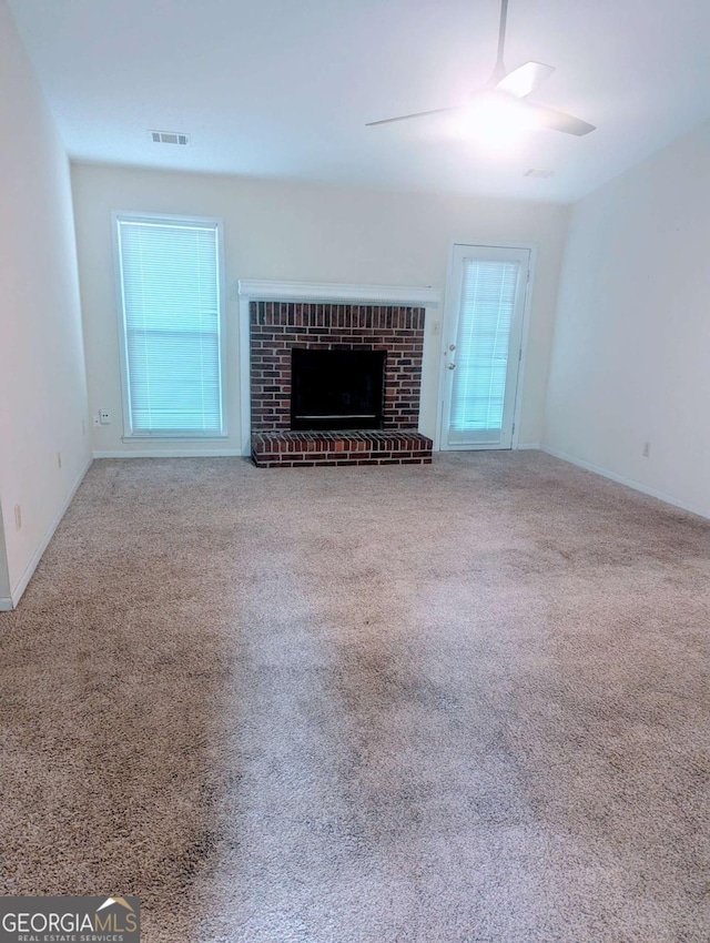 unfurnished living room featuring ceiling fan, carpet floors, and a brick fireplace