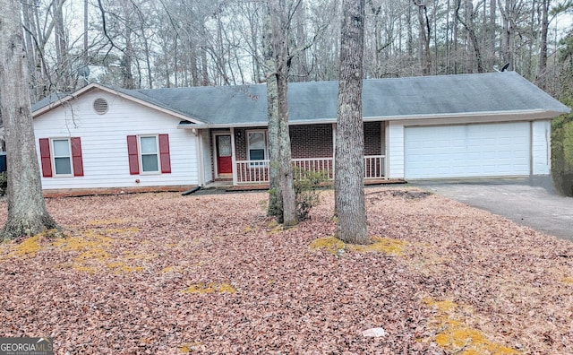 ranch-style home with aphalt driveway, covered porch, and an attached garage