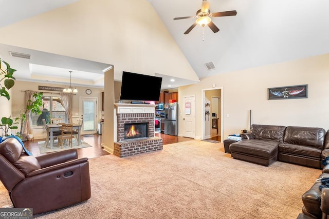 living room featuring light carpet, a tray ceiling, a fireplace, and ceiling fan