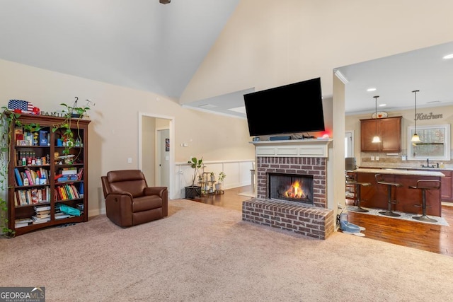 carpeted living room featuring crown molding, high vaulted ceiling, and a brick fireplace