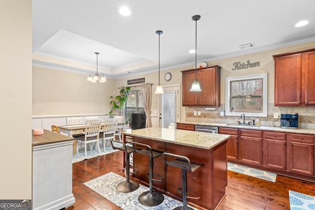 kitchen featuring sink, a tray ceiling, dark hardwood / wood-style flooring, a kitchen island, and pendant lighting