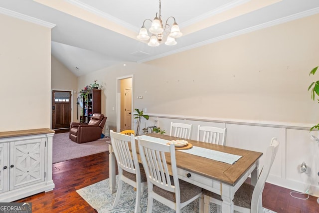 dining room featuring lofted ceiling, crown molding, an inviting chandelier, a tray ceiling, and dark hardwood / wood-style flooring