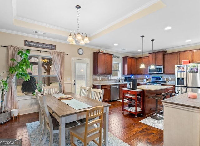 dining space with crown molding, sink, a tray ceiling, and dark wood-type flooring