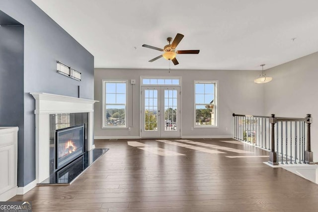 unfurnished living room featuring a fireplace, dark hardwood / wood-style floors, ceiling fan, and french doors