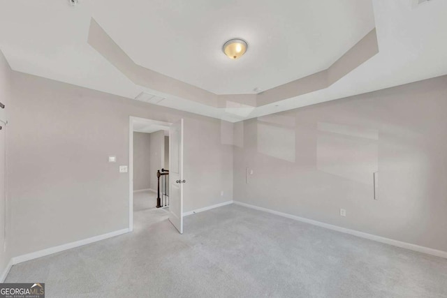 unfurnished room with light colored carpet and a raised ceiling