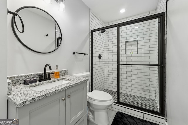 bathroom featuring vanity, an enclosed shower, and toilet