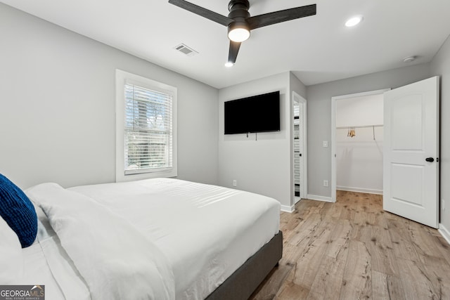 bedroom with ceiling fan, a spacious closet, a closet, and light hardwood / wood-style flooring