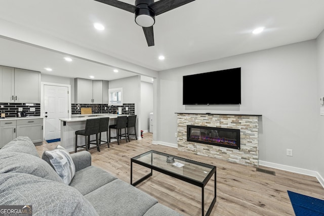 living room featuring a fireplace, light hardwood / wood-style flooring, and ceiling fan