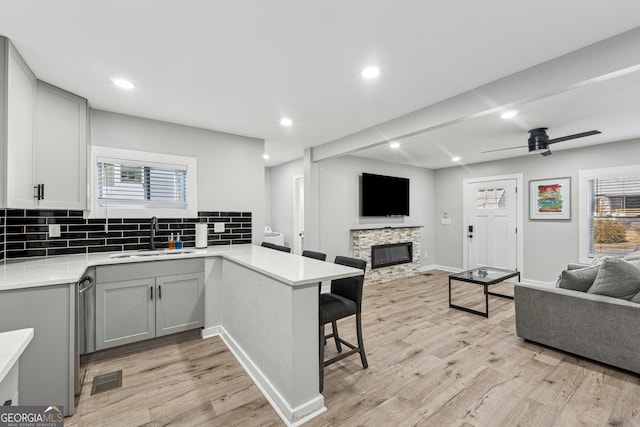 kitchen featuring gray cabinetry, sink, kitchen peninsula, and a breakfast bar