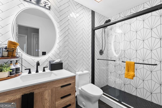 bathroom with a shower with door, vanity, tile walls, and toilet