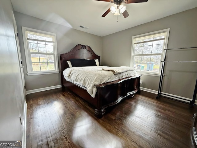 bedroom with dark hardwood / wood-style flooring, ceiling fan, and multiple windows