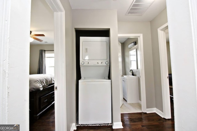 washroom featuring sink, ceiling fan, dark hardwood / wood-style floors, and stacked washer and clothes dryer