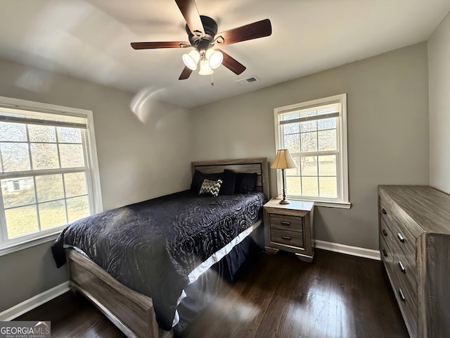 bedroom featuring multiple windows, dark wood-type flooring, and ceiling fan