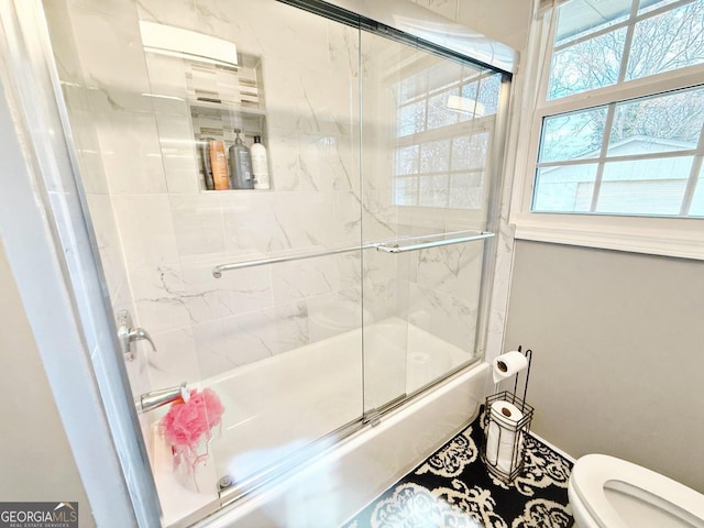 bathroom featuring enclosed tub / shower combo and toilet