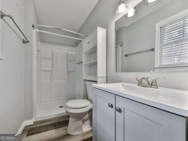 bathroom with hardwood / wood-style flooring, vanity, a textured ceiling, a shower, and toilet